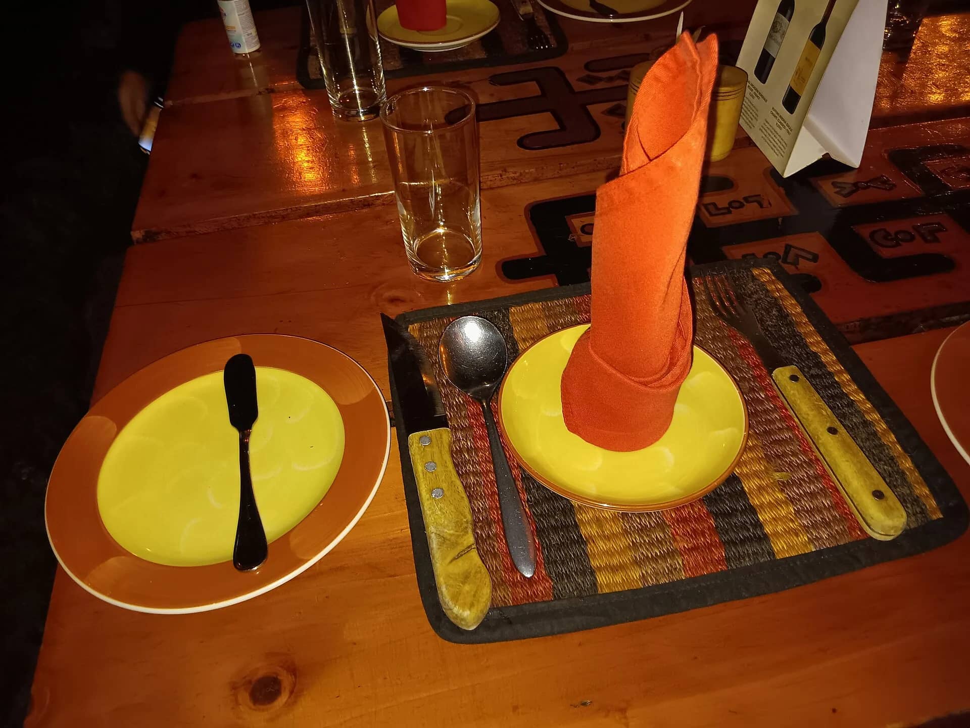 A table laid for dinner at a Kenyan restaurant, woven mat and folded napkin