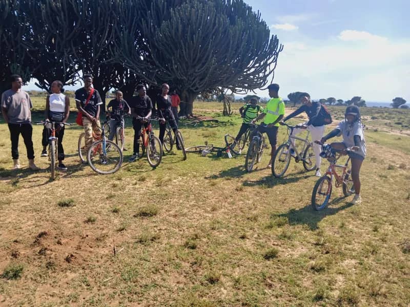 Riders lined up with their bicycles on open grassland before setting off