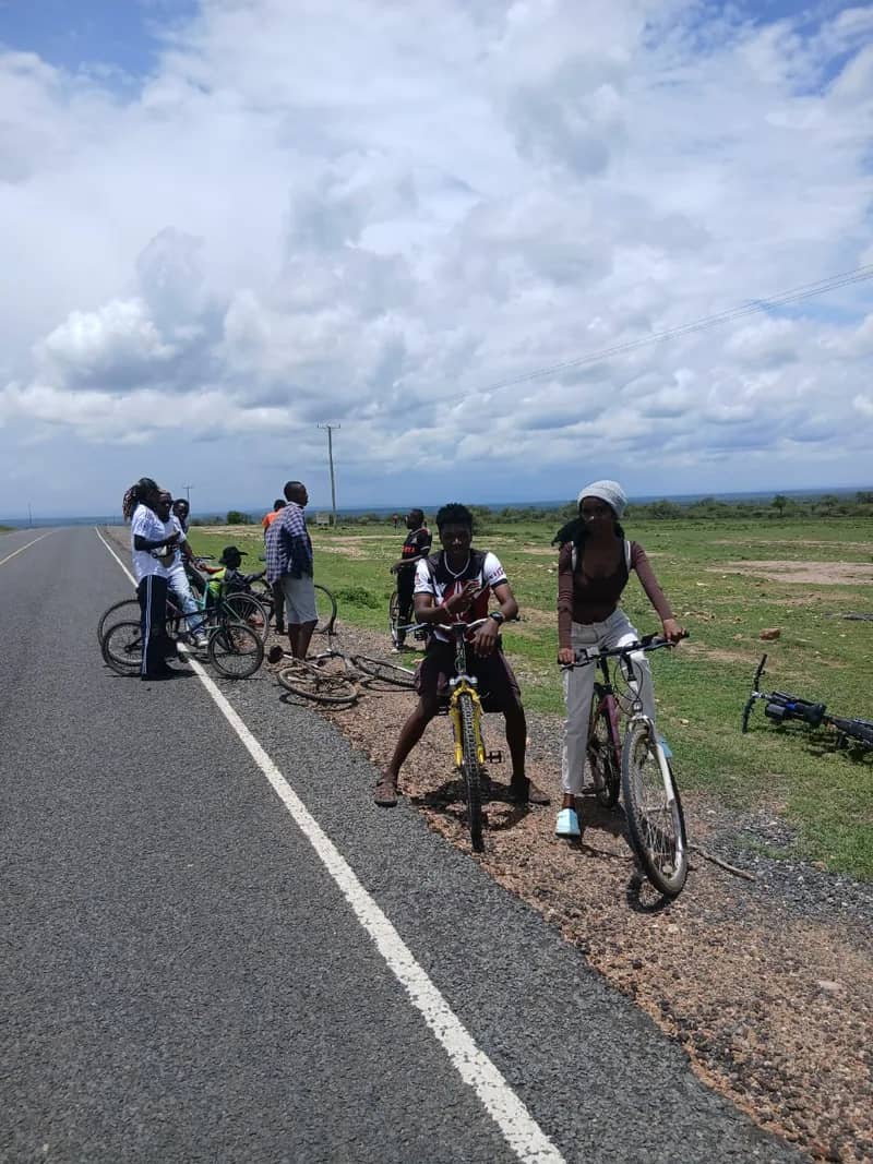 HikeQuest riders resting with their bikes on the verge of a highway under a big sky