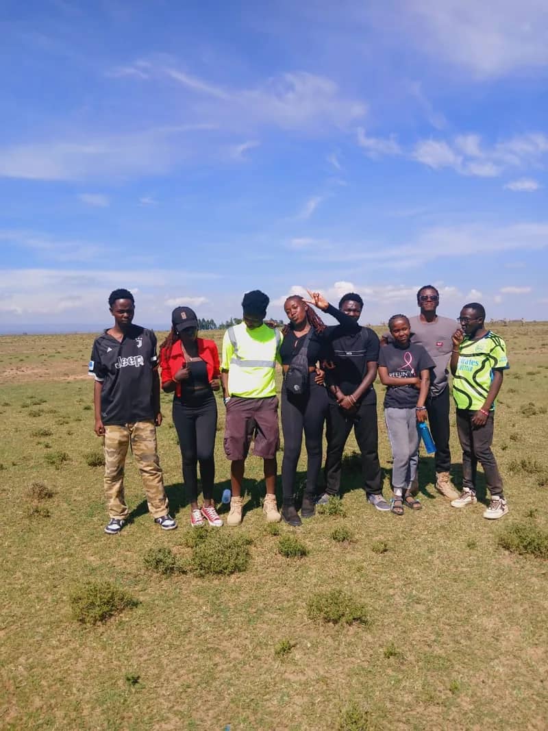 The HikeQuest crew standing together on open grassland under a blue sky
