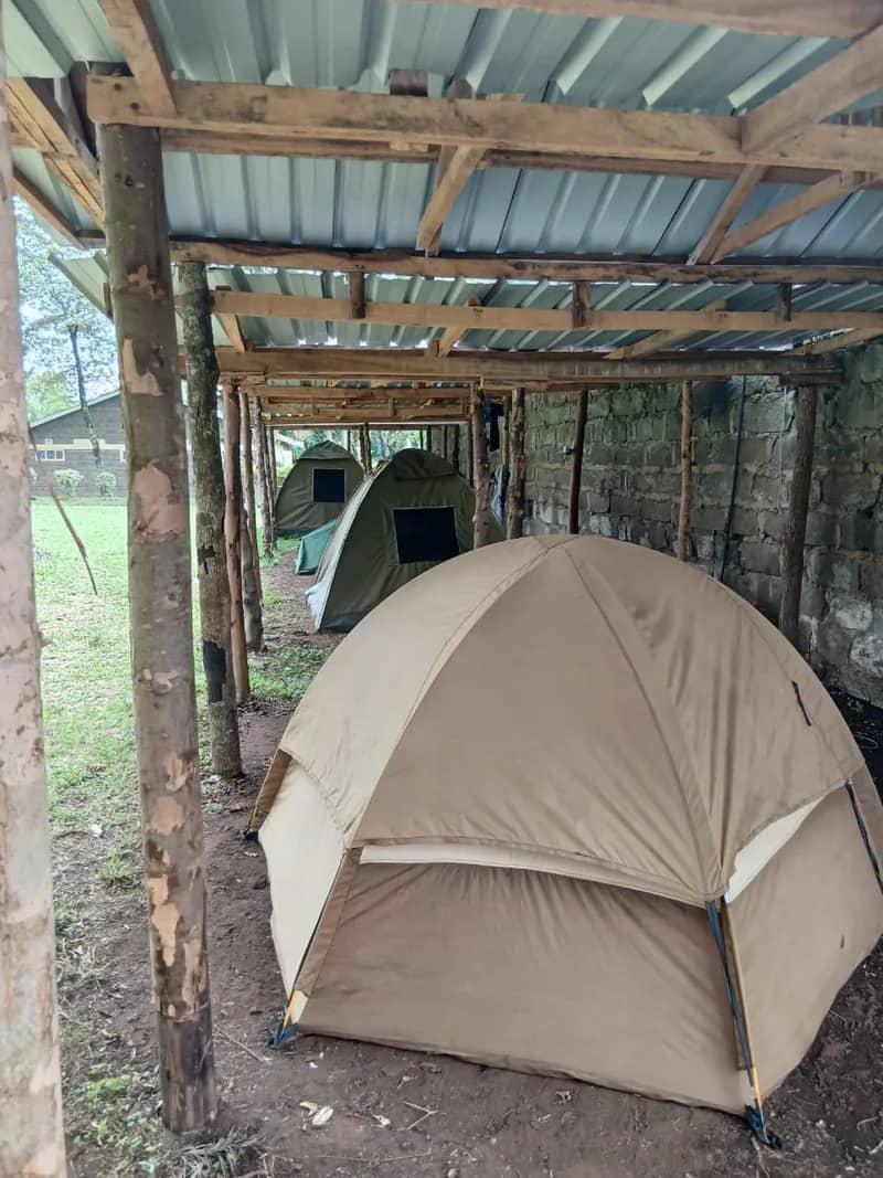 A beige dome tent pitched at a HikeQuest campsite with more tents behind it
